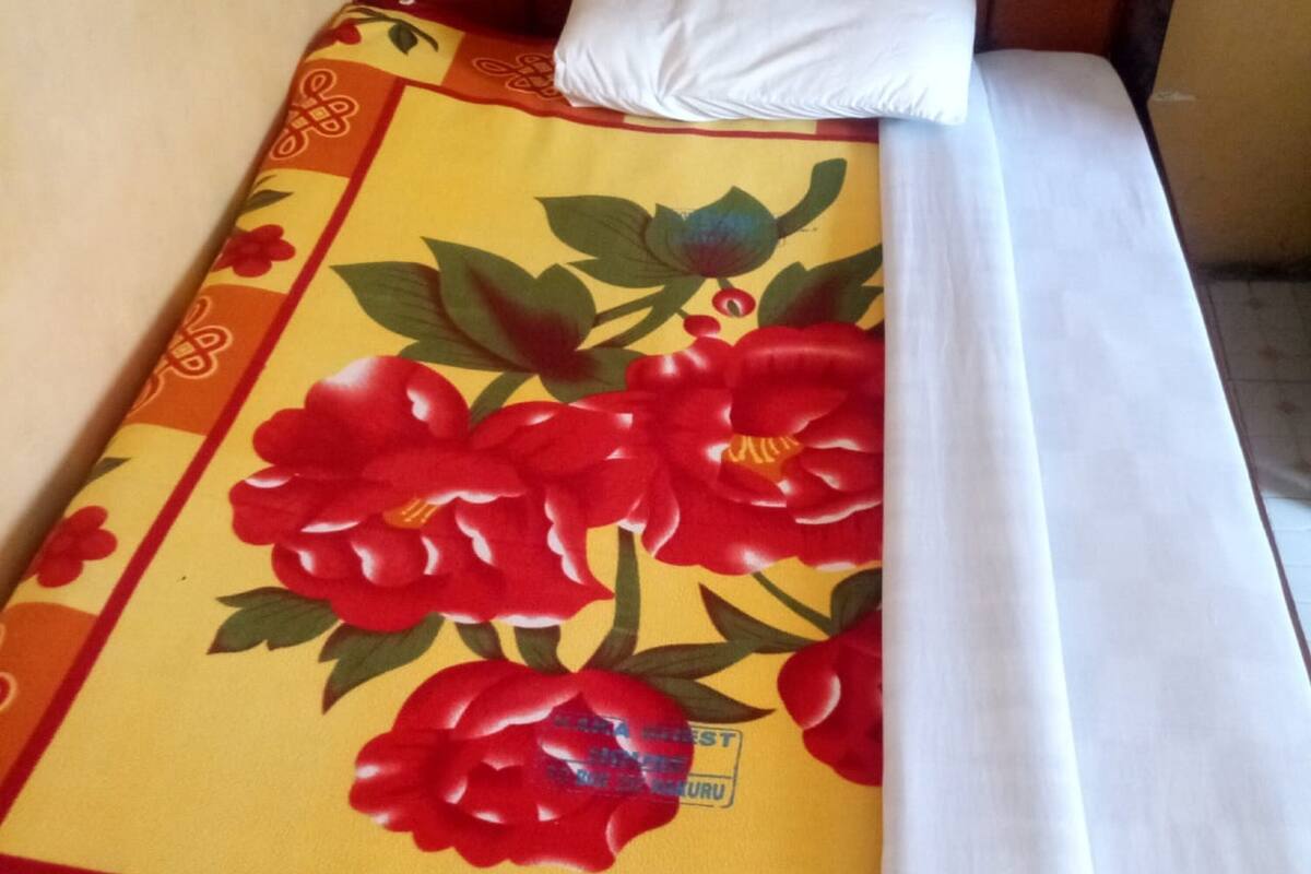 Una cama con una colcha estampada con motivos florales y sábanas blancas.