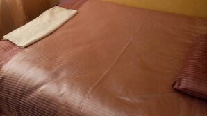 Una cama individual con una colcha a rayas y una manta doblada.