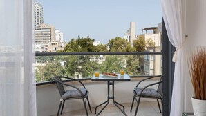 A balcony with two chairs, a small table, and a potted plant. - Pinsker 1BR corner Bograshov by HolyGuest (Tel Aviv-Yafo)