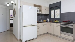 A modern kitchen with a white refrigerator, stainless steel stove, and light-colored cabinets. - Pinsker 1BR corner Bograshov by HolyGuest (Tel Aviv-Yafo)