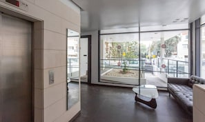 A modern lobby with a glass door leading outside, a sofa, and a coffee table. - White House 3BR in Gordon Beach by HolyGuest (Tel Aviv-Yafo)