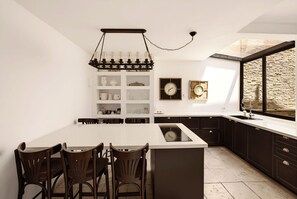 Une cuisine moderne dotée d’un îlot central, de meubles de rangement aux couleurs sombres et d’une grande fenêtre.