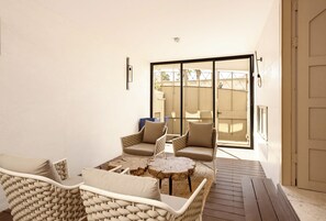 A sunlit patio with wicker furniture, a small round table, and a sliding glass door leading to a covered outdoor area. - 4BR Family House in Neve Tsedek with Mamad by Holyguest (Tel Aviv-Yafo)