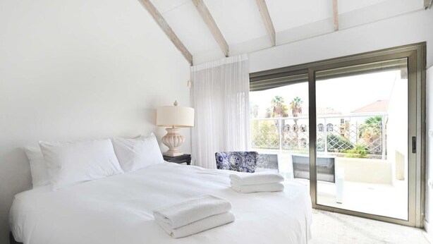 Une chambre d’hôtel avec un grand lit, une lampe, une vue sur le balcon extérieur et une porte-fenêtre coulissante.