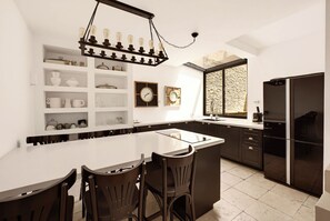 A modern kitchen with a central island, dark cabinetry, and a hanging light fixture.