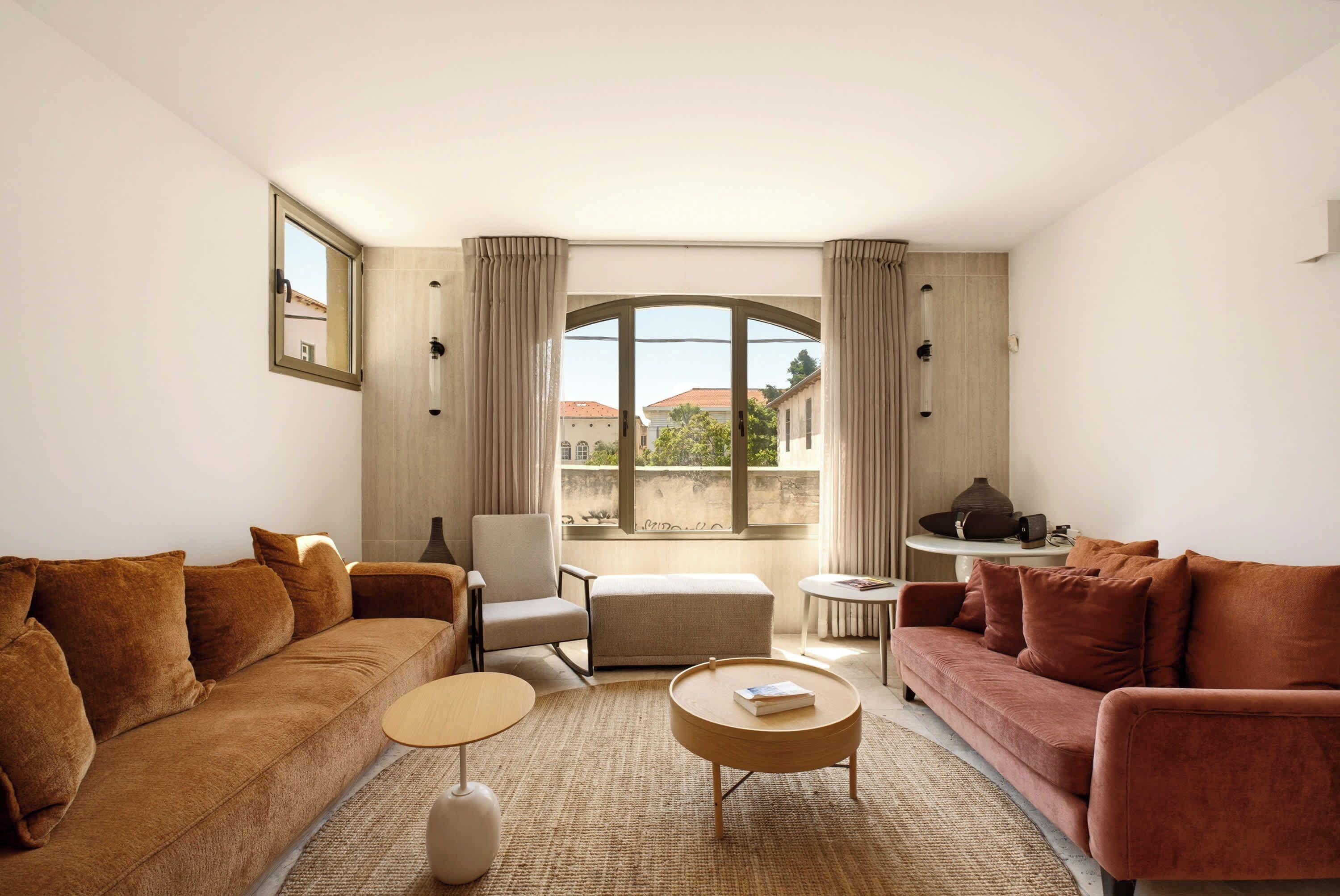 A living room with a sofa, armchair, ottoman, coffee table, and a small side table with a lamp.
