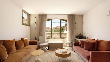 A living room with a sofa, armchair, ottoman, coffee table, and a small side table with a lamp.