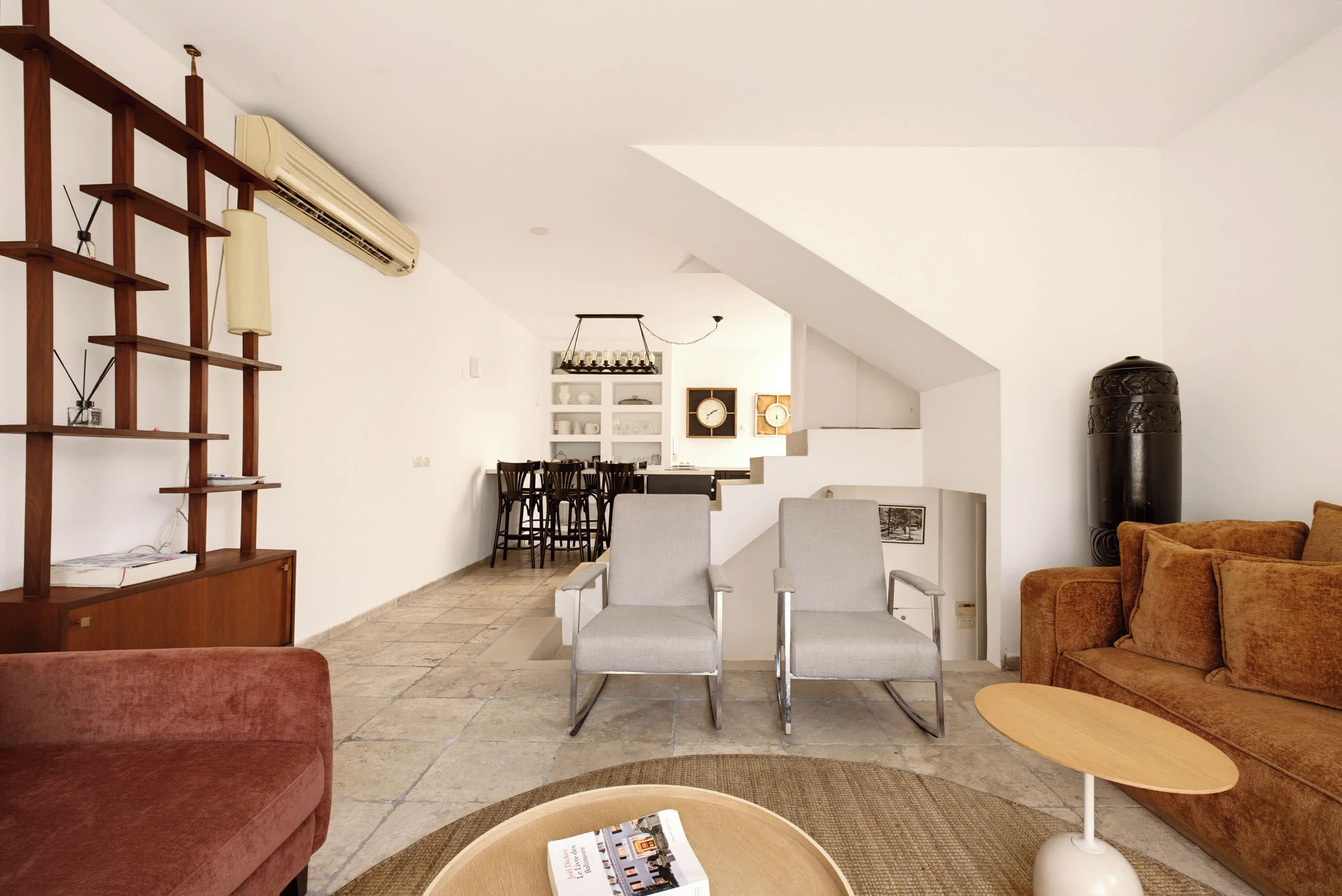 A modern living room with a sofa, armchairs, a coffee table, and a bookshelf.
