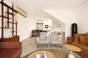 Ein modernes Wohnzimmer mit einer Couch, Sesseln, einem Couchtisch und einem Bücherregal.