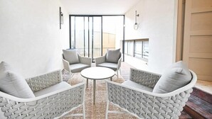 Un intérieur moderne avec un ensemble de canapés blancs, une table ronde et une vue sur l’extérieur grâce à de grandes portes vitrées.