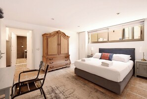 Ein Hotelzimmer mit einem Bett, einem Kleiderschrank, einem Stuhl, einem Nachttisch und einem Spiegel.