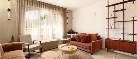Una sala de estar moderna con sofá, sillón, mesa de centro y aparador de madera con estantes.