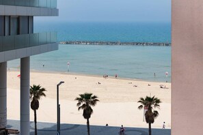 A beach view with palm trees and a pier in the background. - At Renoma Stunning 2BR with Sea View by HolyGuest (Tel Aviv-Yafo)