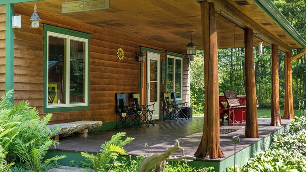 A wooden cabin with a covered porch, outdoor seating, and a stone ledge. - Quiet Cabin in the Woods - Secluded Yet Close to It All (Levering)