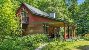 A rustic cabin with a porch, surrounded by lush greenery and trees. - Quiet Cabin in the Woods - Secluded Yet Close to It All (Levering)