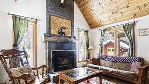 A cozy living room with a fireplace, wooden furniture, and a colorful rug. - Quiet Cabin in the Woods - Secluded Yet Close to It All (Levering)