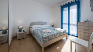 Um quarto com uma cama, mesas de cabeceira, cômoda e uma cadeira.