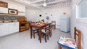 A modern kitchen with white cabinets, a gas stove, and a dining area with wooden chairs and a table.
