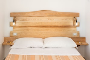 A bed with a wooden headboard, two bedside tables, and a light fixture. - I Tre Golfi Casa Marina (San Vito Lo Capo)