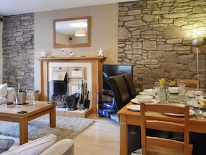Ein gemütliches Wohnzimmer mit Steinwand, Kamin und Essbereich, der für eine Mahlzeit gedeckt ist.