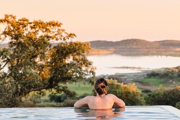 Una piscina al aire libre, sombrillas, sillones reclinables de piscina