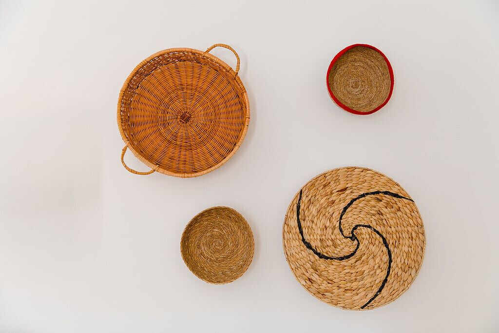 Four woven baskets of different sizes and designs on a plain background.