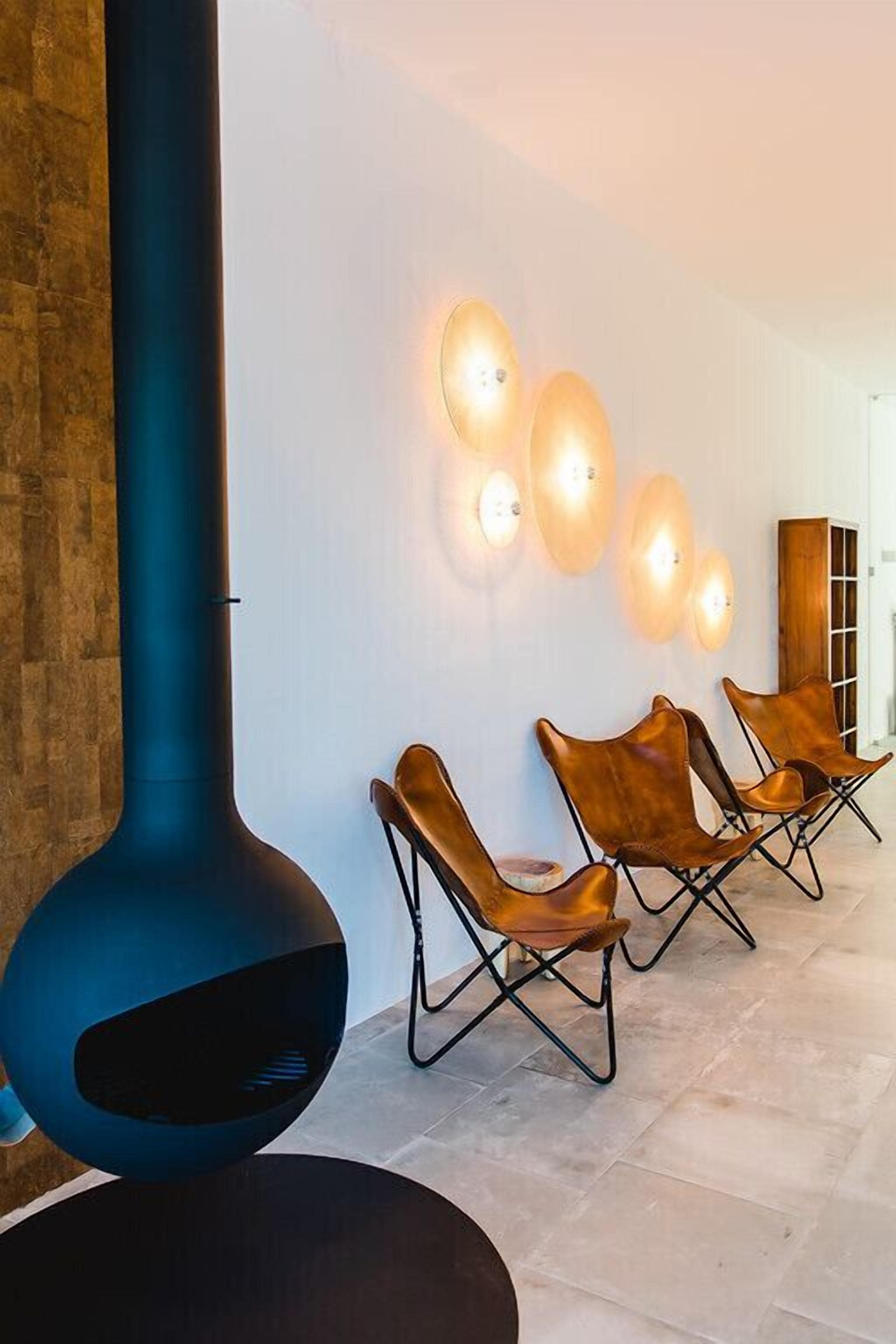 A modern interior with a large blue sculpture, leather chairs, and wall-mounted lighting.
