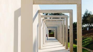 Un couloir bordé d’une série de cadres blancs qui mène à l’entrée d’un bâtiment.