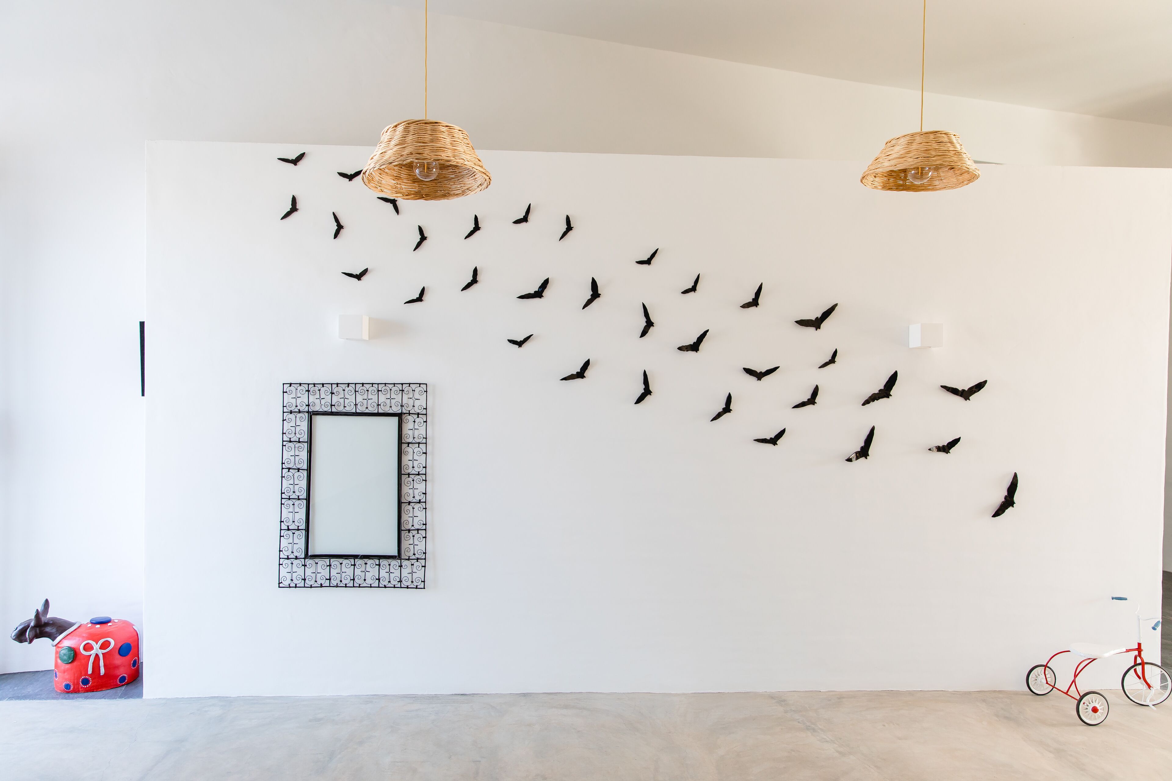 Ein Zimmer mit weißer Wand, einem Spiegel mit dekorativem Rahmen und einem roten Spielpferd.