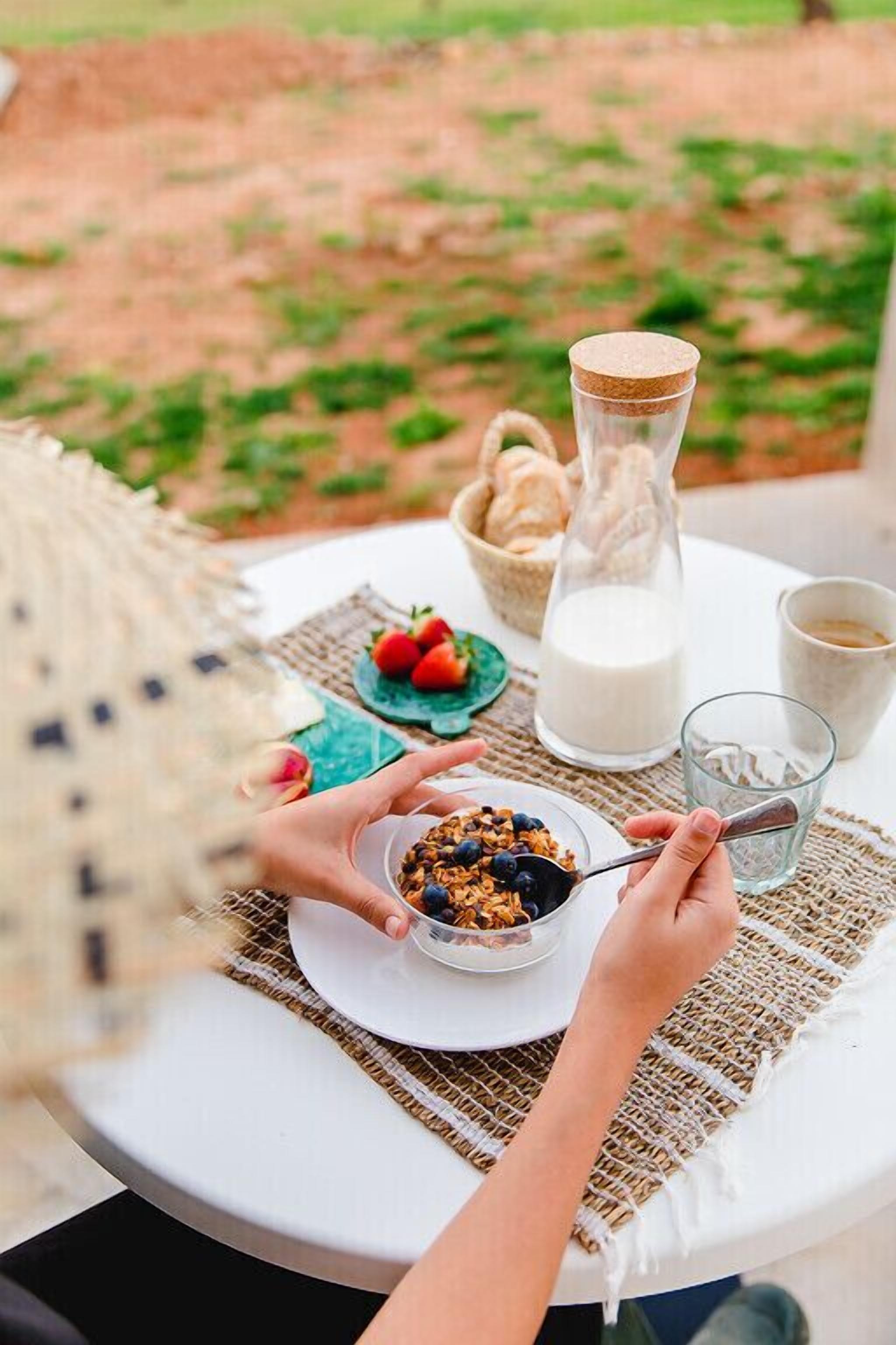 A breakfast setting with a plate of cereal, a glass of milk, and a glass of water on a table.
