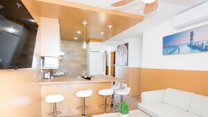 Eine moderne Küche mit einer Holzausziehtheke, Barhocker, einem weißen Sofa und einem Deckenventilator.