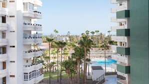 Ein modernes Hotel mit mehreren Balkonen, einem Pool und Palmen.