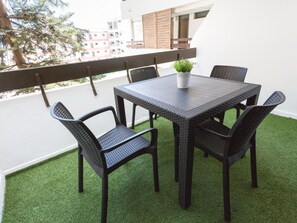 A balcony with a table and chairs, a small potted plant, and a view of buildings in the background. - Ocean Friendly Holiday Home (Playa del Inglés)