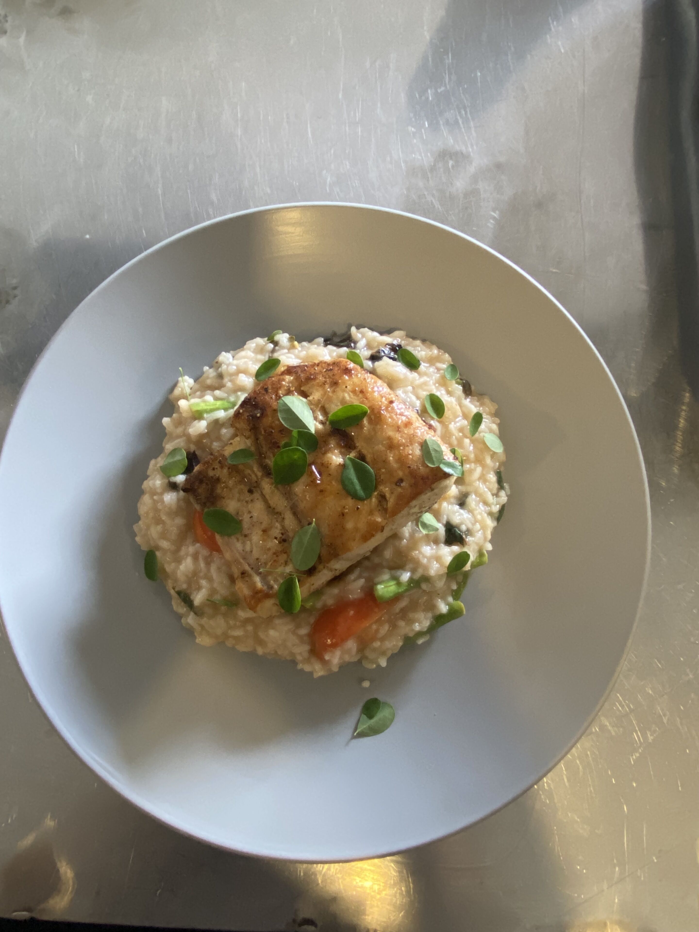 Une assiette de nourriture composée de riz, de légumes et d’un morceau de viande, le tout servi dans une assiette blanche.