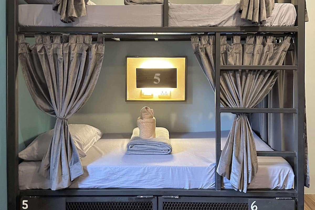 A bunk bed room with curtains, a number 5 sign, and a small towel on the lower bunk.