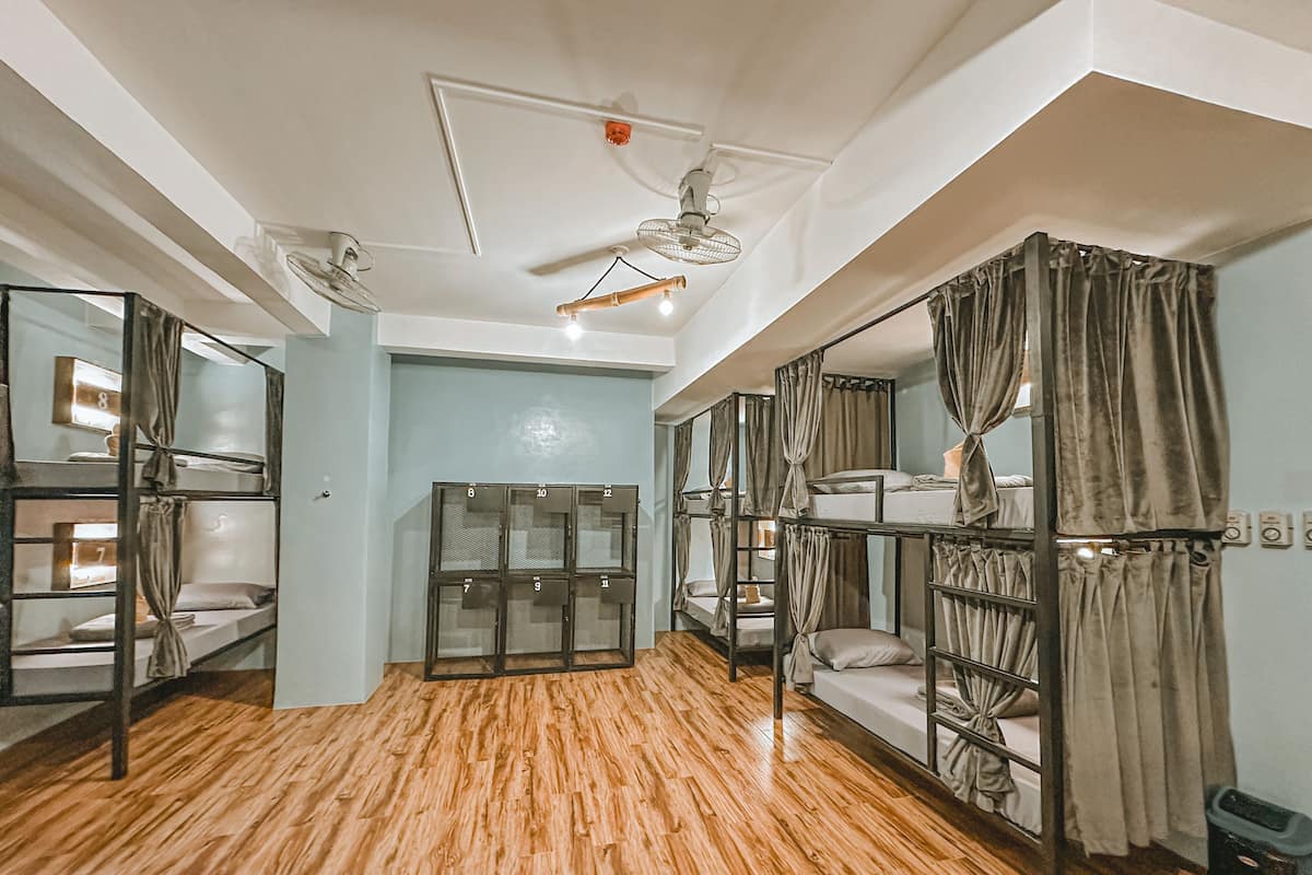 A dormitory room with bunk beds, a ceiling fan, and a wooden floor.