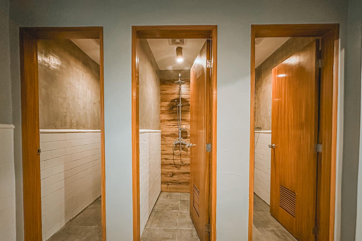 A hallway with three wooden doors, white tiled walls, and a tiled floor.