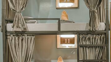 A bunk bed with curtains, a wooden number sign, and a folded towel on the lower bunk.