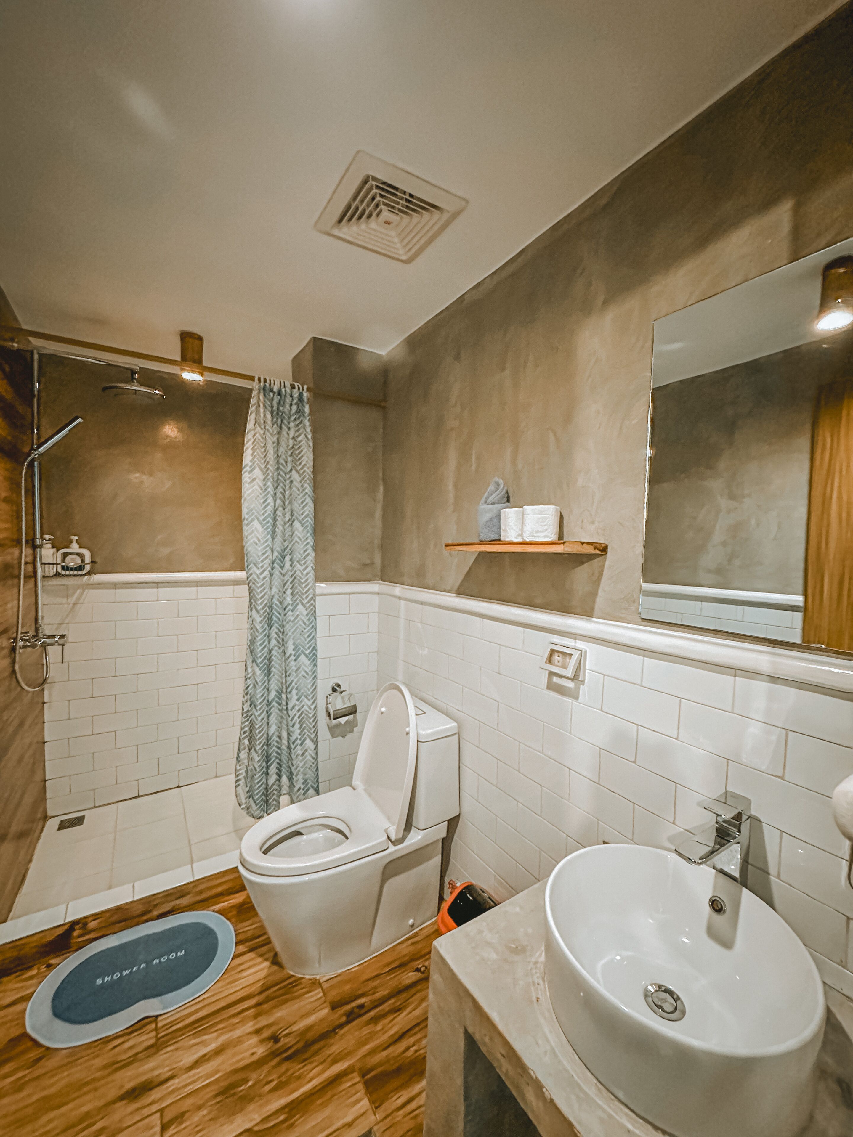 Een badkamer met douche, toilet, wastafel en spiegel.