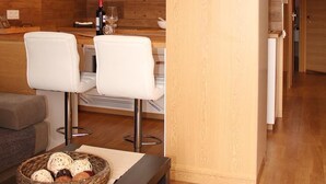 Eine moderne Küche mit Holzschränken, ein Essbereich mit weißen Stühlen und einem Deckenventilator.