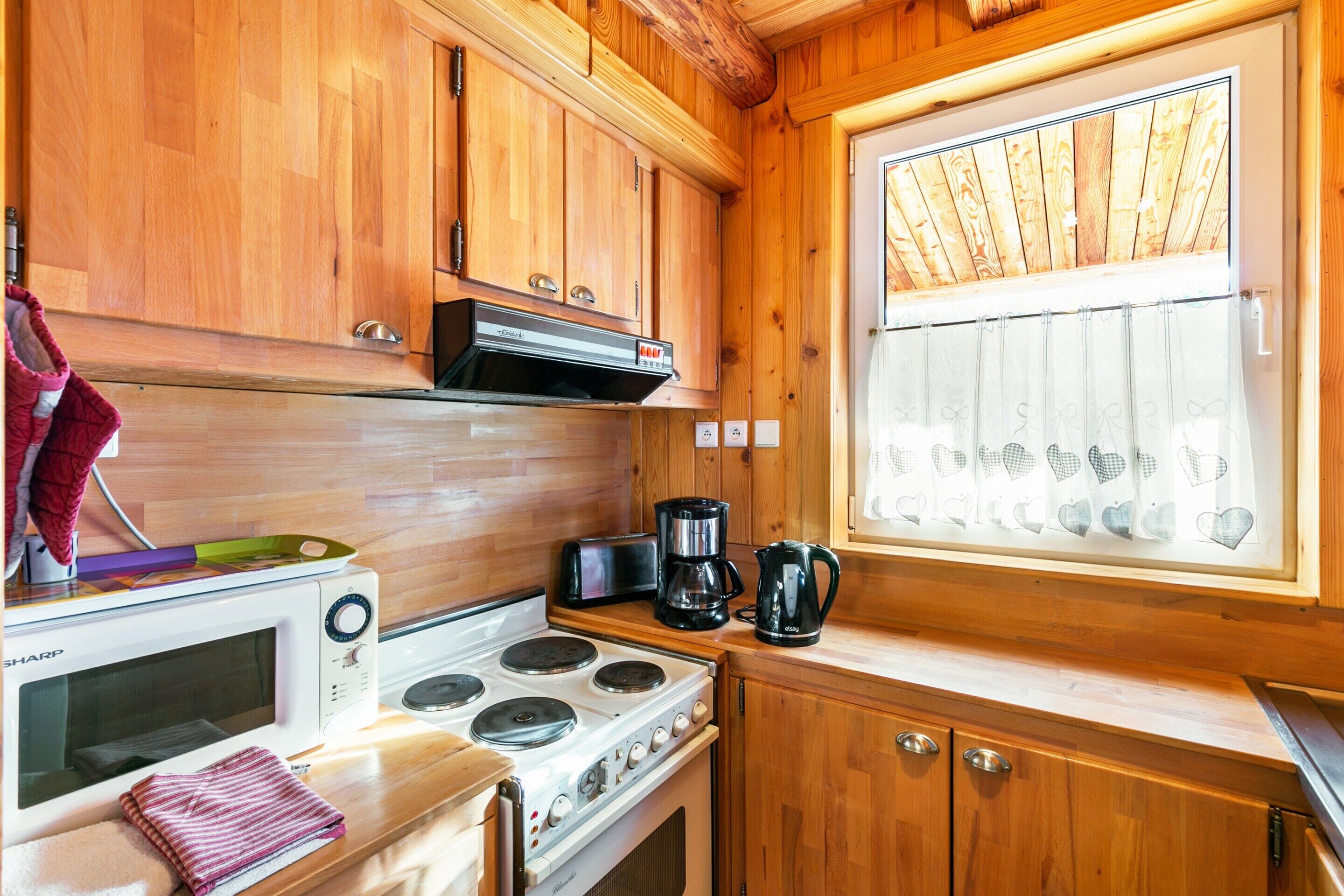 A wooden kitchen with a stove, microwave, and coffee maker.