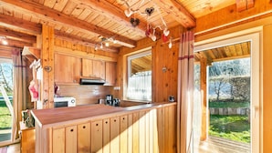 Interior de madera con cocina, que incluye armarios, una encimera y un ventanal.