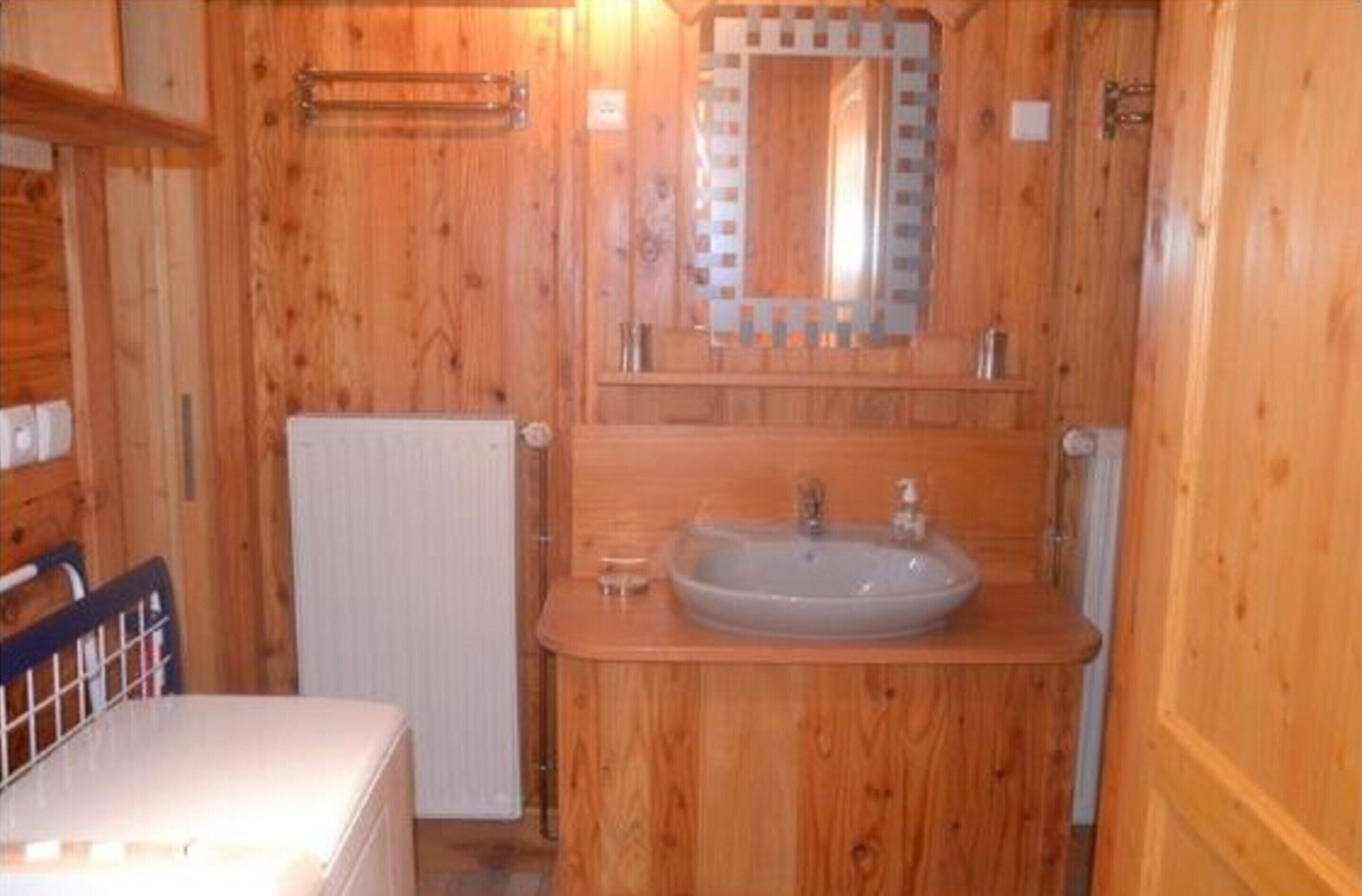 Ein Badezimmer aus Holz mit Waschbecken, Spiegel und Handtuchhalter.