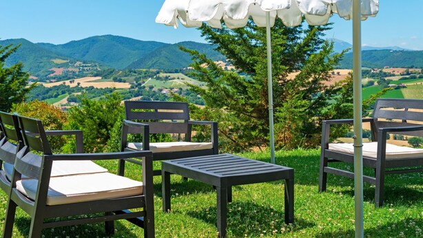 Un espace extérieur aménagé avec deux chaises et une table, un parasol et une vue sur un paysage montagneux.