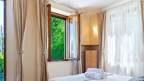 Une chambre à coucher avec un lit, une fenêtre, une commode et une lampe.