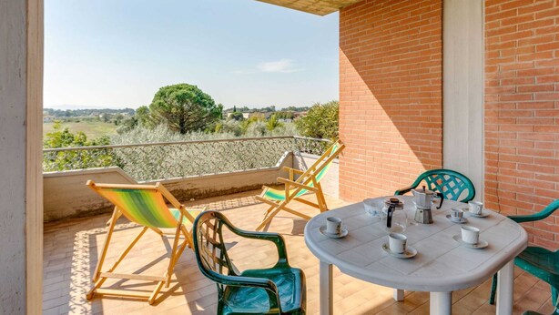 A balcony with a table set for tea, chairs, and a view of the countryside. - Apartment in Tuscany Near Lake Trasimeno (Tuoro sul Trasimeno)