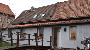 Ein Haus mit Teich, Holzbrücke und einem draußen abgestellten Fahrrad.