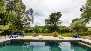 A swimming pool with lounge chairs, surrounded by trees and greenery. - Flat in a Beautiful Building With Pool (Meze)