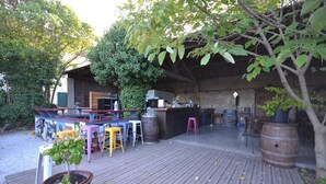 An outdoor bar area with wooden flooring, a bar counter, stools, and a potted plant. - Flat in a Beautiful Building With Pool (Meze)