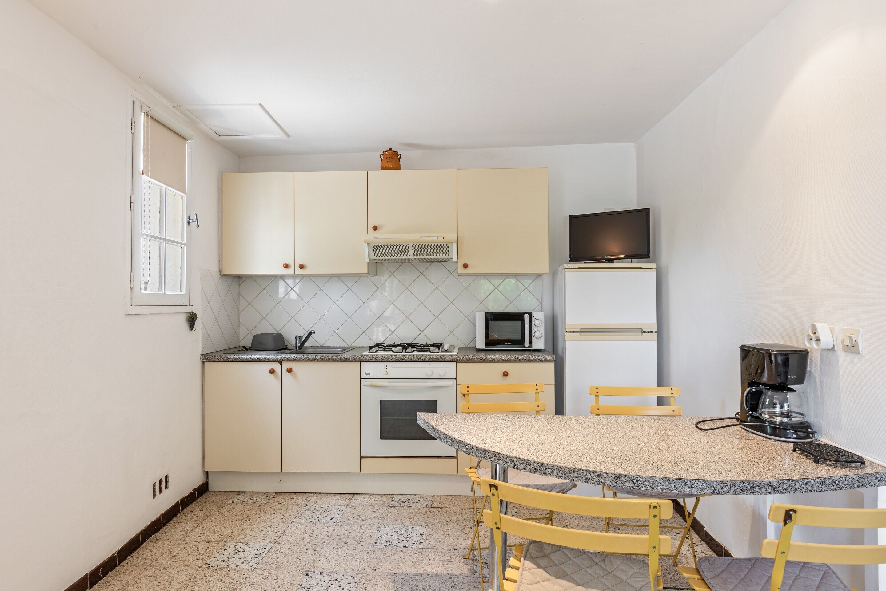 A compact kitchen with a dining area, a microwave, a stove, and a coffee maker.
